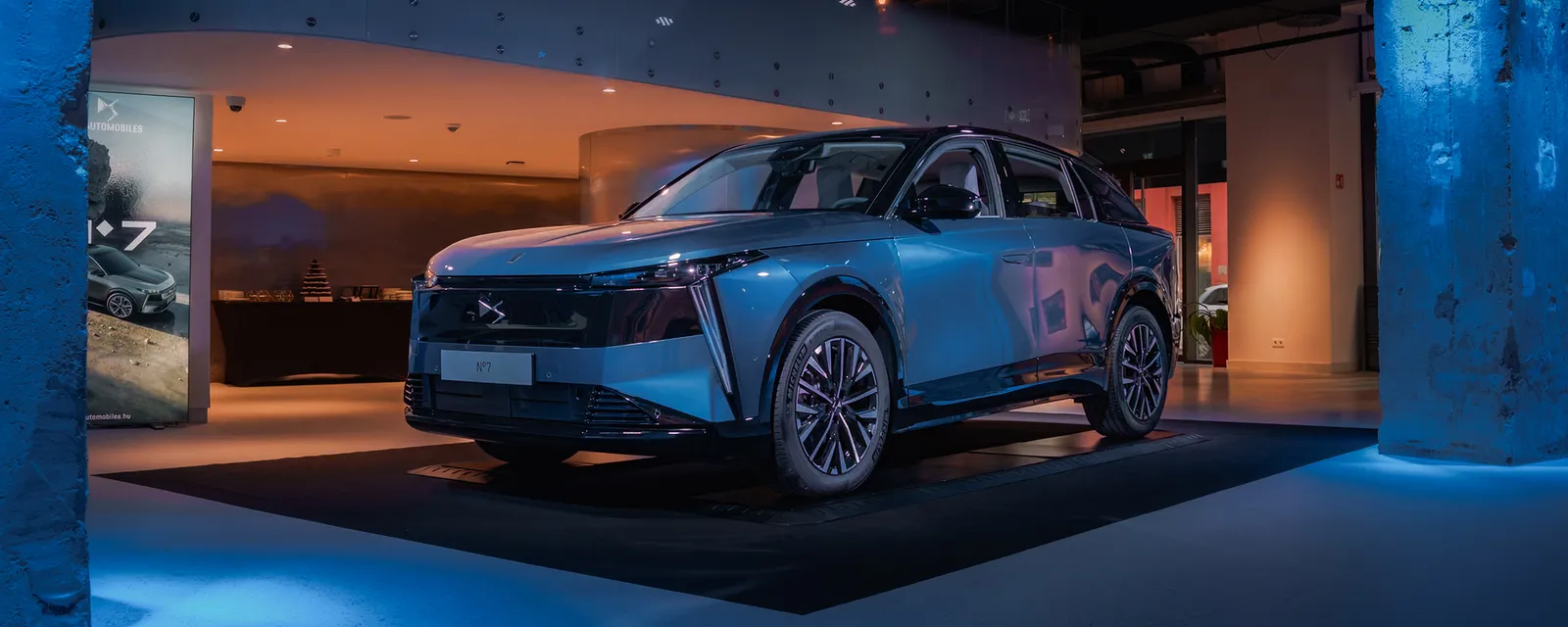 Kék SUV kiállítva egy autós termékbemutató sötét, kékre világított terében