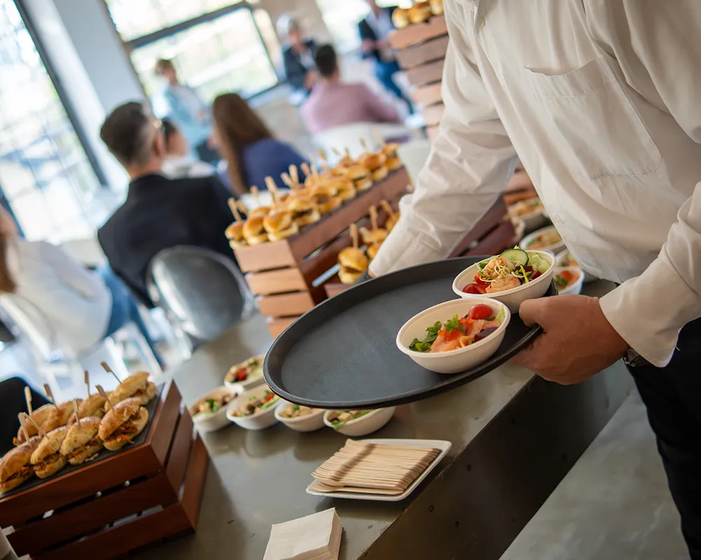 Felszolgáló fogásokat tálal a catering pultnál