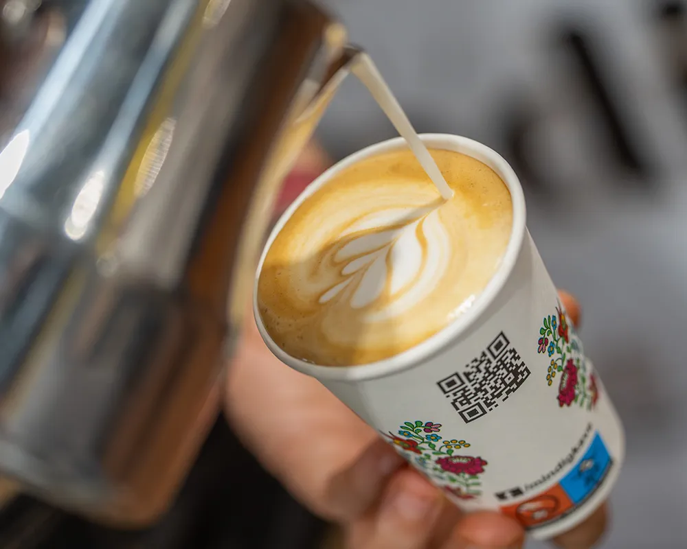 Latte art kávé papírpohárban, közeli kép